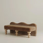 Brown velvet bench with wooden legs on a beige background
