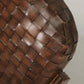 Close-up of a woven brown leather bag on a light background