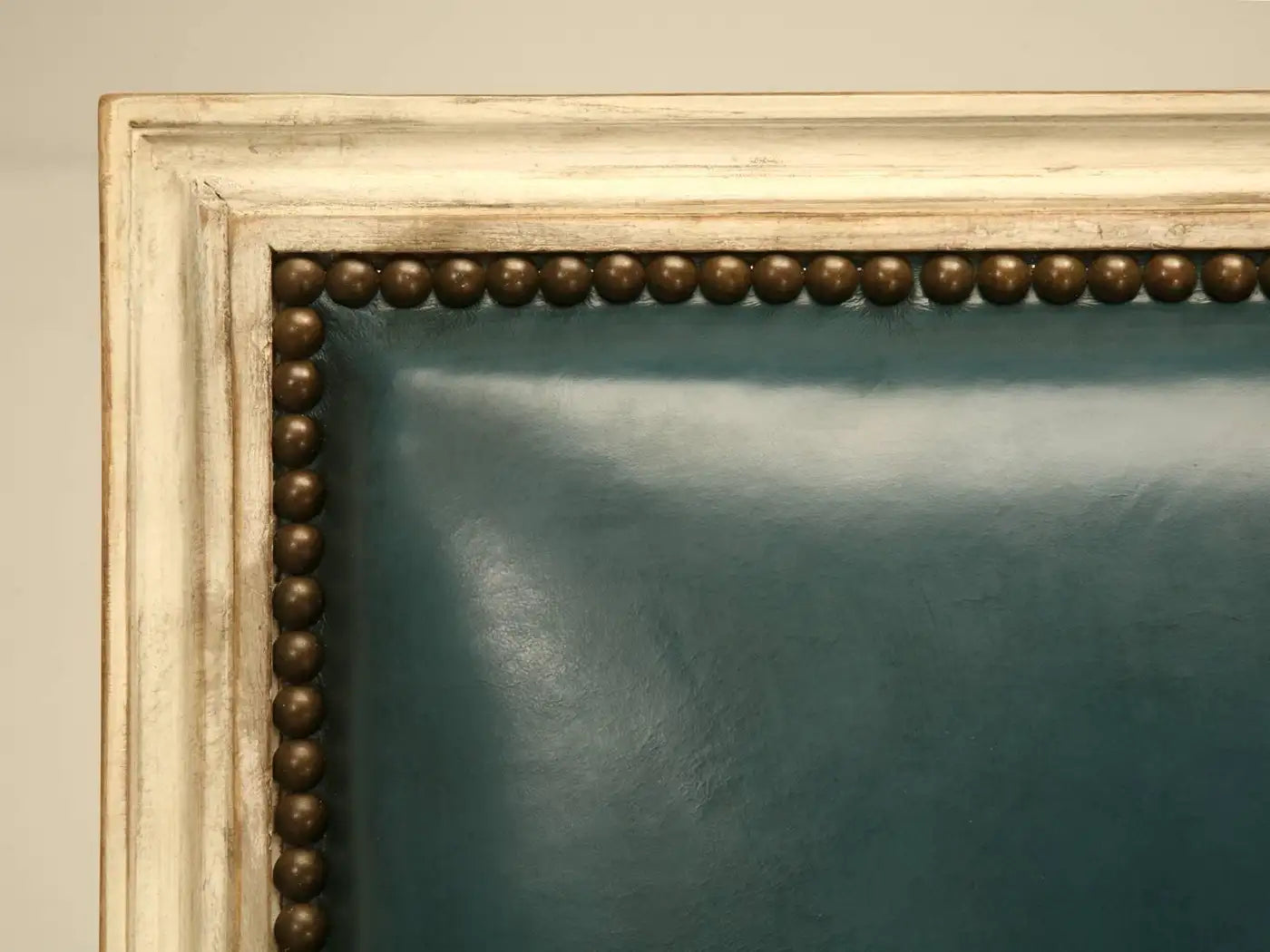 Close-up of a decorative gold frame with a textured border on a beige wall.