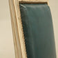 Teal fabric draped over a wooden frame against a beige wall