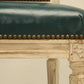 Vintage chair with green leather seat and brass nailhead trim on a beige background