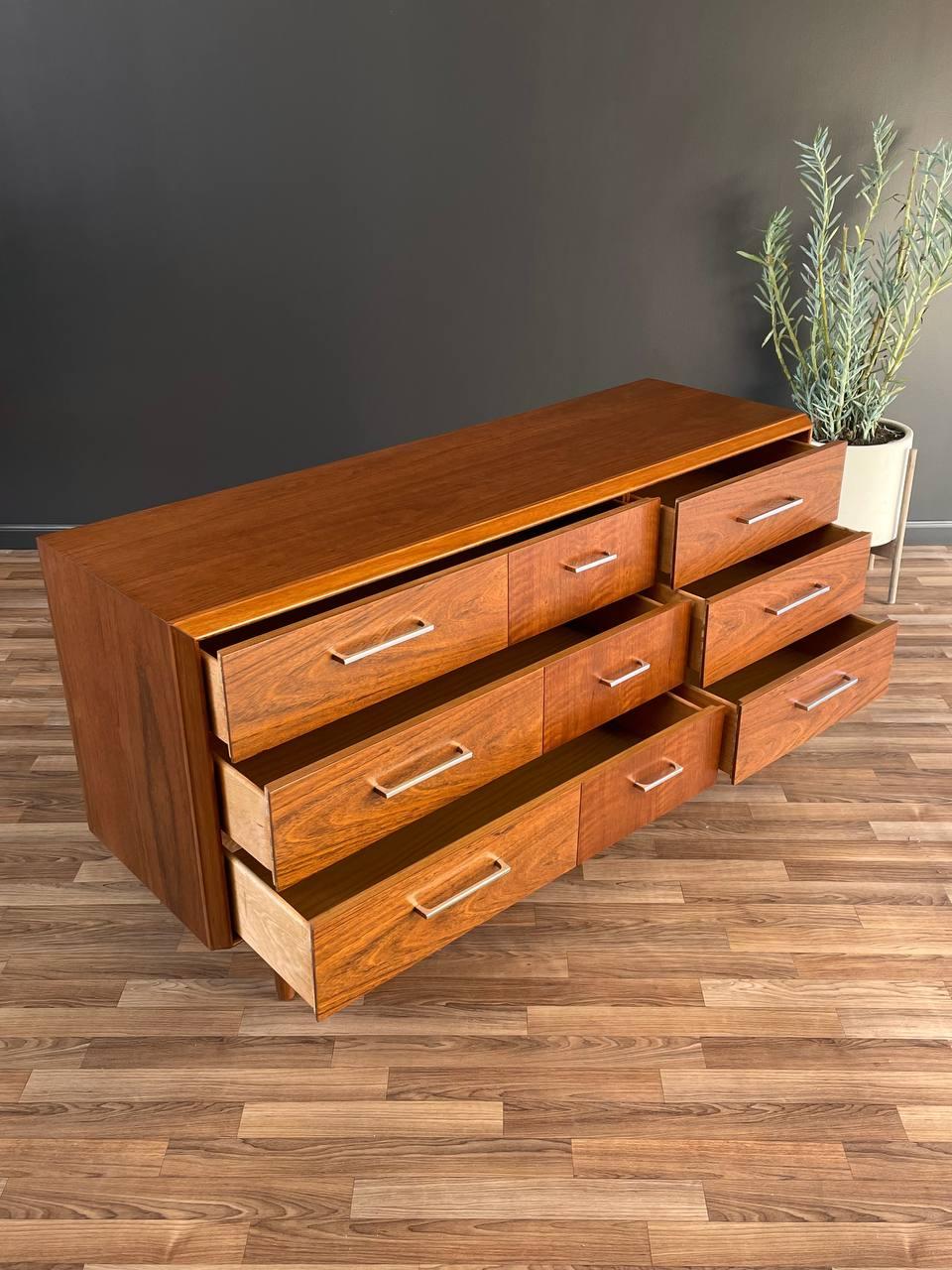 Wooden dresser with multiple drawers on a wooden floor.