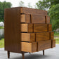 Wooden dresser with multiple drawers outdoors on a paved surface with greenery in the background