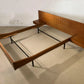 Wooden bed frame with headboard on a concrete floor.