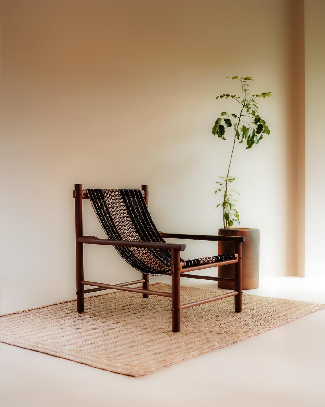 Wooden chair with woven backrest in a minimalistic room with a plant and rug.