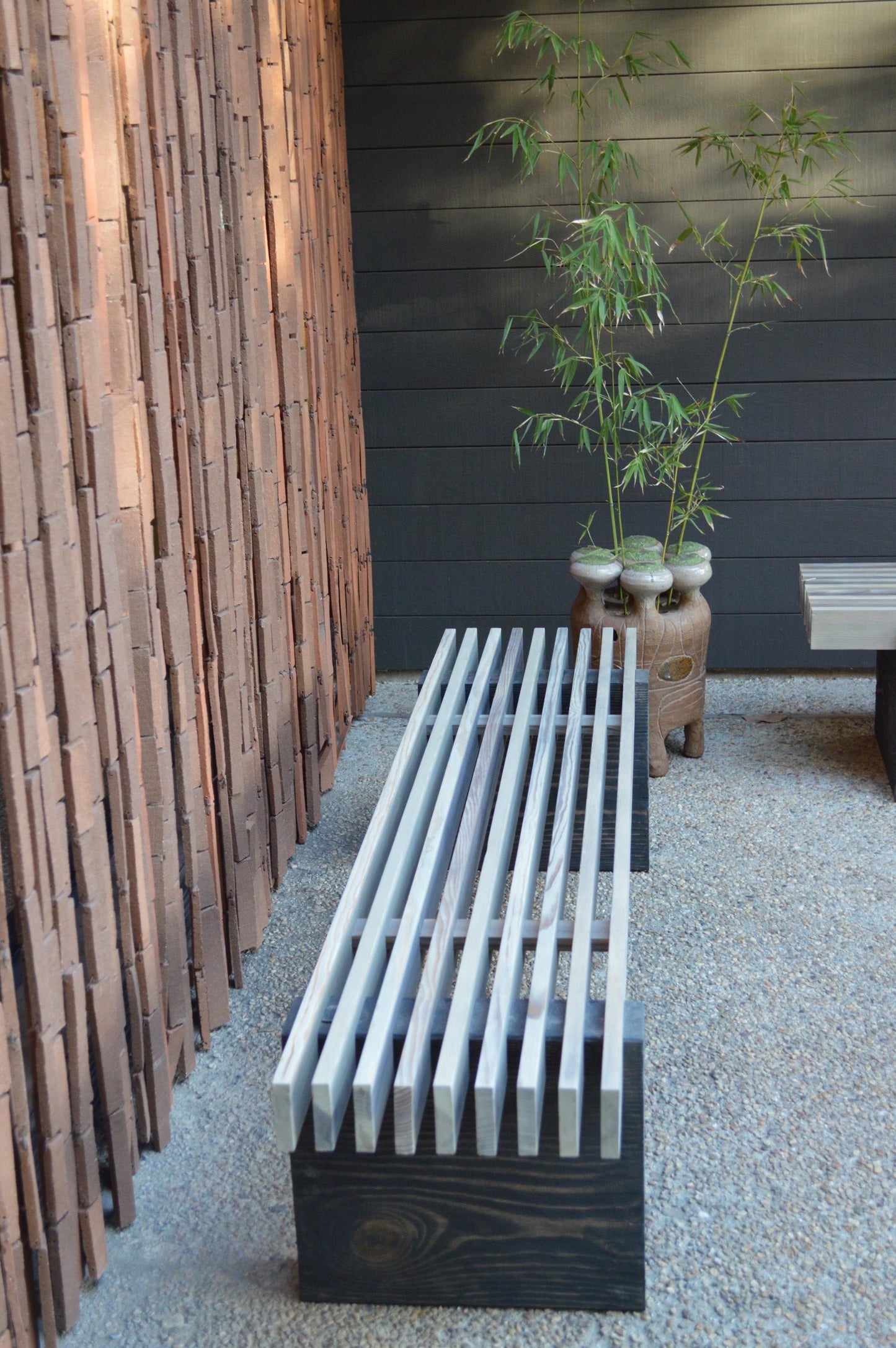 Wooden bench against a wall with a plant in the background