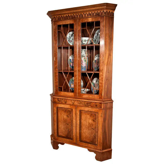Wooden corner cabinet with glass doors displaying decorative plates on a white background
